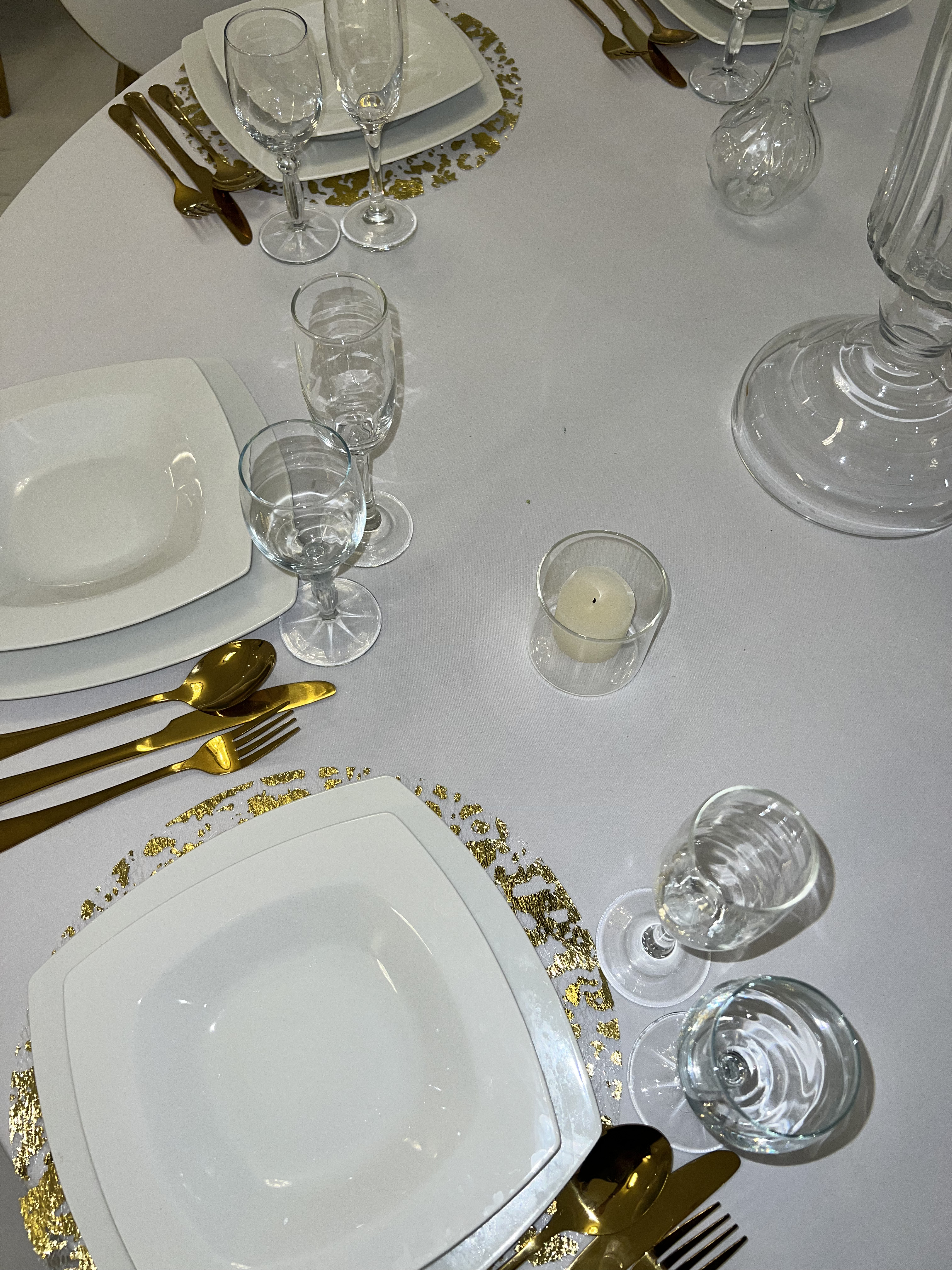 Détail d'art de la table au Palace Victory Events - Assiettes carrées blanches, couverts dorés et bougie