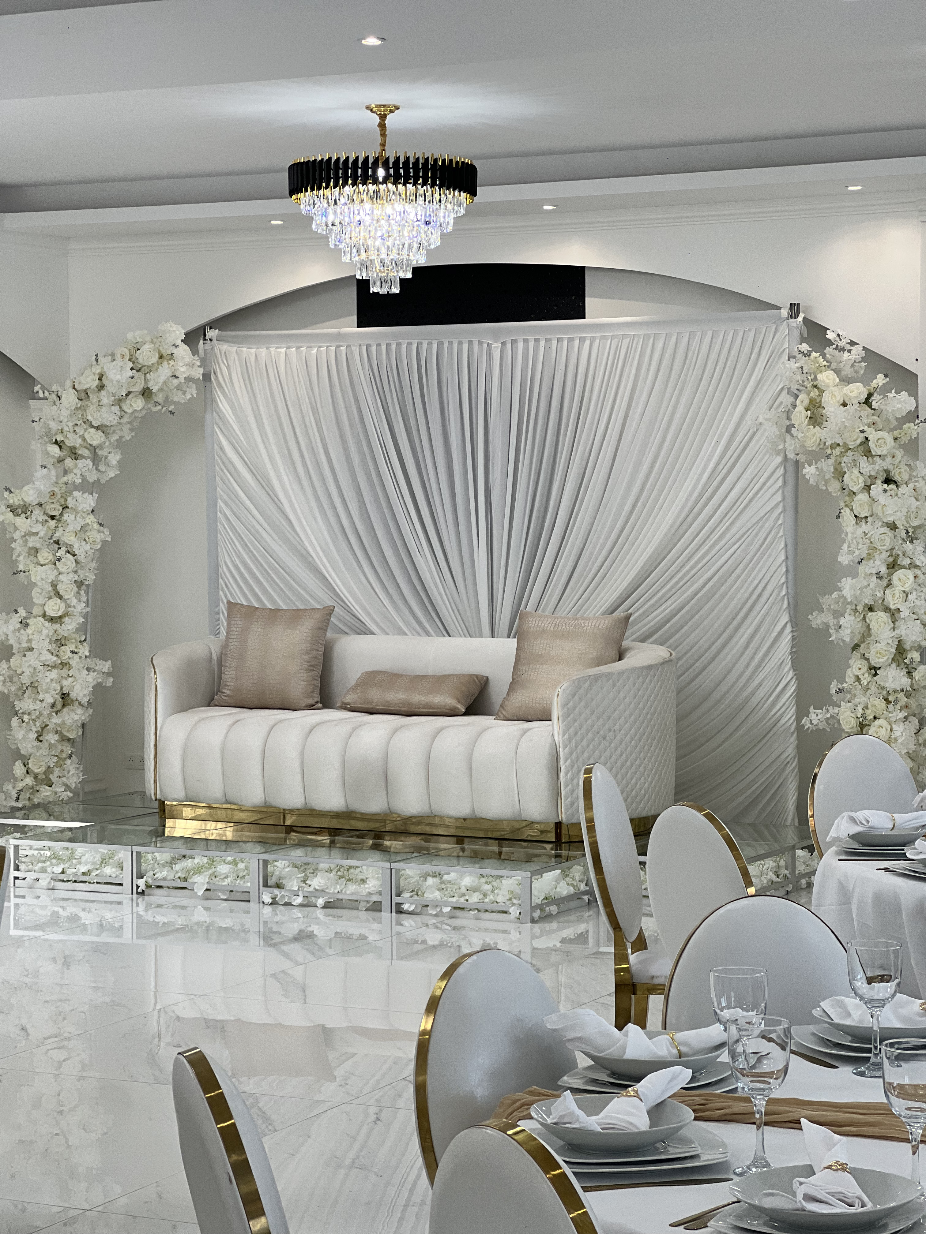 Espace lounge du Palace Victory Events - Canapé crème capitonné sur estrade miroir avec arches de roses blanches et drapé