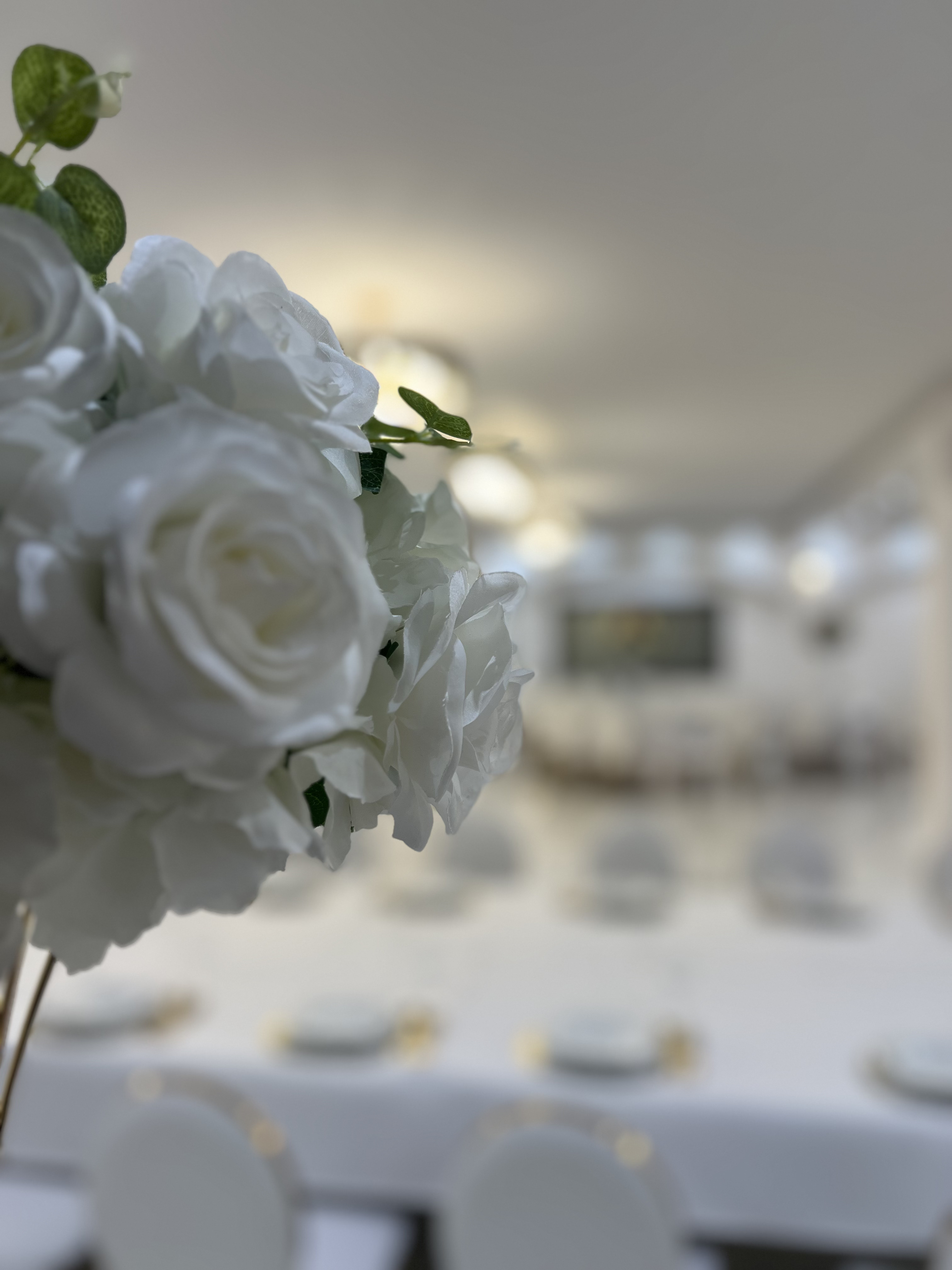 Détail d'une composition de roses blanches au Palace Victory Events avec salle de réception en arrière-plan