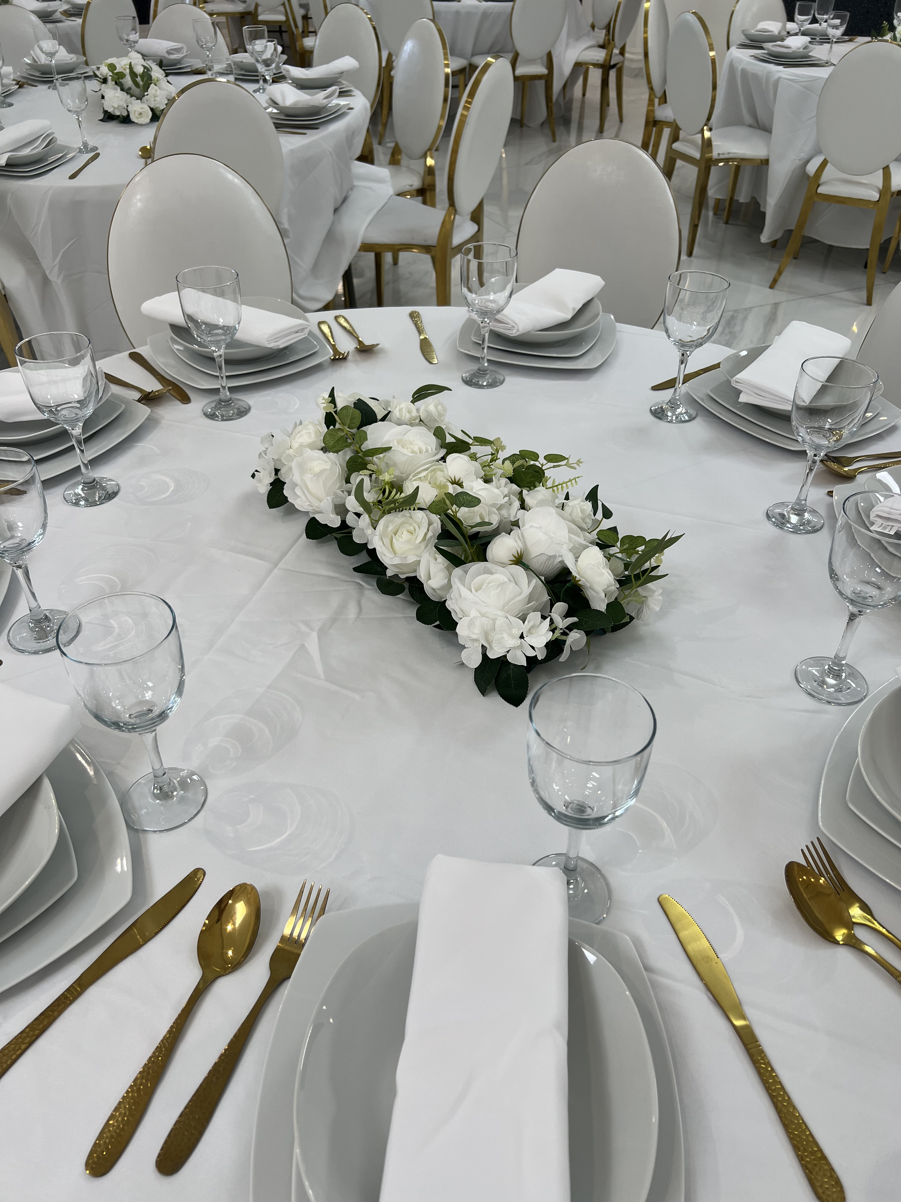 Table ronde dressée au Palace Victory Events - Centre floral blanc, couverts dorés et vaisselle blanche